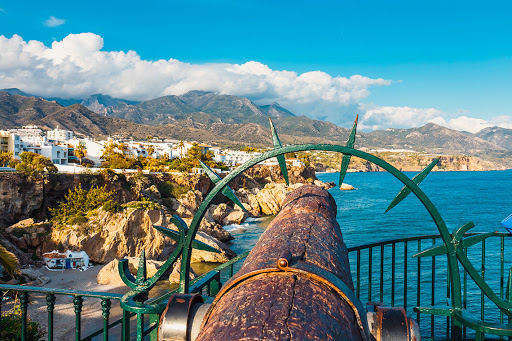 a view of a cliff overlooking the ocean with mountains in the background