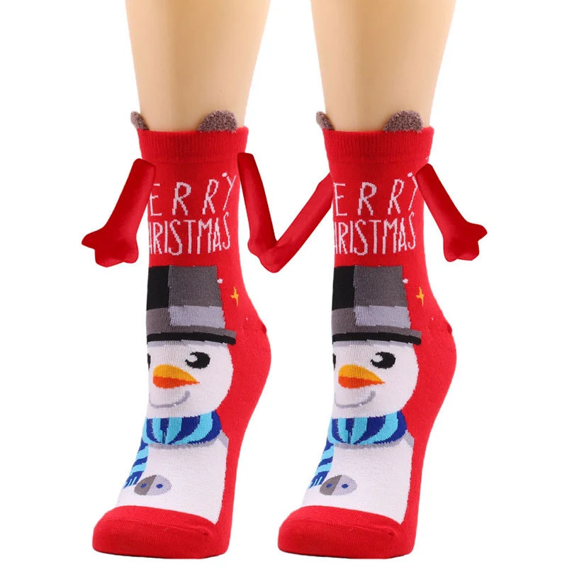 Mão segurando casal com alça magnética meias de Natal