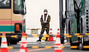 A Japanese soldier guards buses as passengers disembark from the coronavirus-hit Diamond Princess cruise ship  at Yokohama, south of Tokyo, Japan, on February 20 2020. 