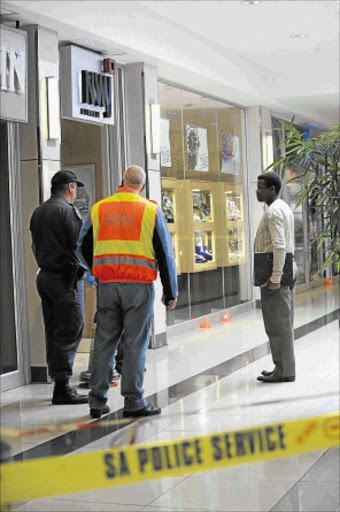 CRIME SCENE: A forensic team and police at the blood-soaked entrance to NWJ jewellery shop in Randridge Mall after an armed robbery. Photo: Tsheko Kabasia