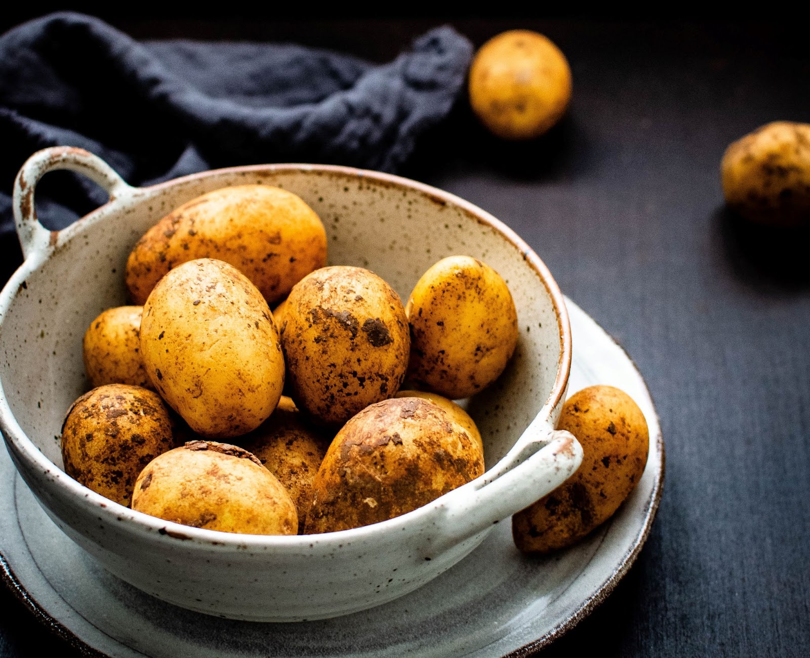 A white bowl of baked potatoes on a table. 