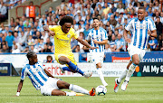 Chelsea's Willian gets away from a challenge from Huddersfield Town's Terence Kongolo during a Premier League match at the John Smith's Stadium on August 11, 2018.