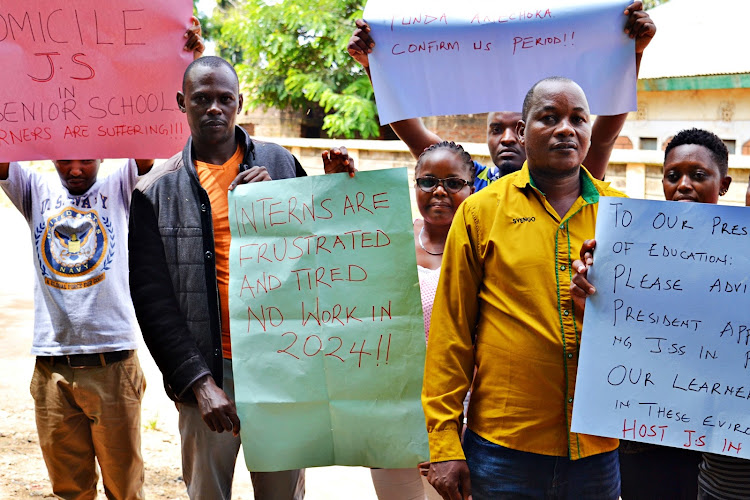 The demonstrating JSS intern teachers wielding a placard communicating their grevancies.