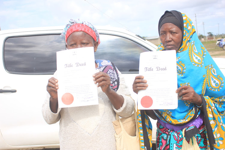 Two women from Mbalamweni in Gotani display the title deeds they received from the government on July 8 at Gotani