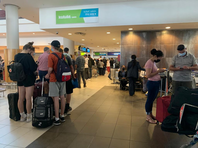 Passengers queue at the Kulula and British Airways counter at Cape Town International Airport after flights were grounded for safety reasons on March 12 2022.