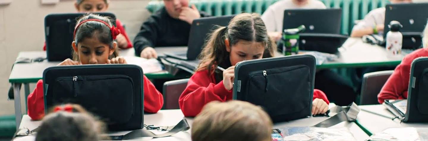 An adult and a child sitting side by side, watching an educational video on a laptop.