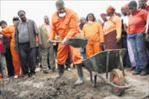 GETTING STUCK IN: Minister of Land and Rural Development Gugile Nkwinti scoops concrete from a wheelbarrow as he helps to build toilets at a school in Muyexe village at the weekend.Pic: CHESTER MAKANA. 19/07/2009. © Sowetan.