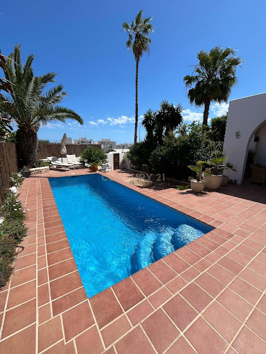 Outdoor pool with loungers and palm trees in this luxury property for sale in Santa Eulària des Riu ($1,823,119)