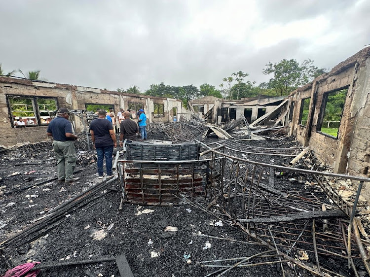 People inside the remains of a burnt secondary school dormitory after several children, most of them from indigenous communities, died after a fire gutted the building overnight in Mahdia, Guyana, in this handout image obtained by Reuters on May 22 2023.