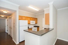 Kitchen next to the dining area with gray countertops, wood cabinets, and white appliances