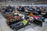 People who fled the war in Ukraine rest inside a temporary refugee shelter that was an abandoned TESCO supermarket after being transported from the Polish Ukrainian border on March 8 2022 in Przemysl, Poland.