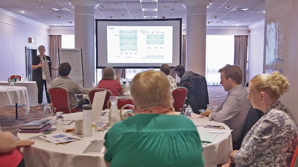 A group of people participating in a workshop. They are watching someone present.