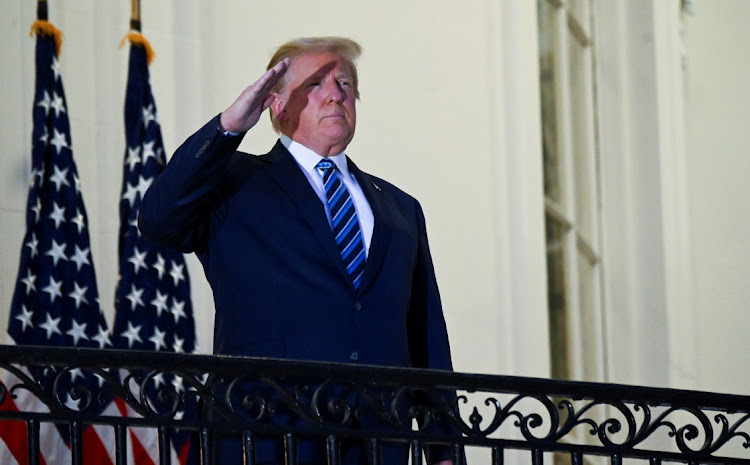 US President Donald Trump salutes as he poses without a face mask on the Truman Balcony of the White House after returning from being Walter Reed Medical Center for Covid-19 treatment in Washington on Monday.