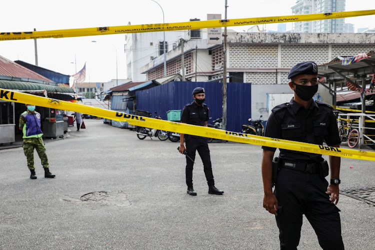 Police officers stand guard at an entrance of a market, during the movement control order due to the outbreak of Covid-19, in Kuala Lumpur, Malaysia,earlier this year. Goldman Sachs has been given a big fine following a corruption scandal in this country.