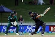 Martin Guptill of New Zealand bats as South Africa's Quinton de Kock (L) watches during the one-day international (ODI) cricket match between New Zealand and South Africa at Seddon Park in Hamilton on March 1, 2017.