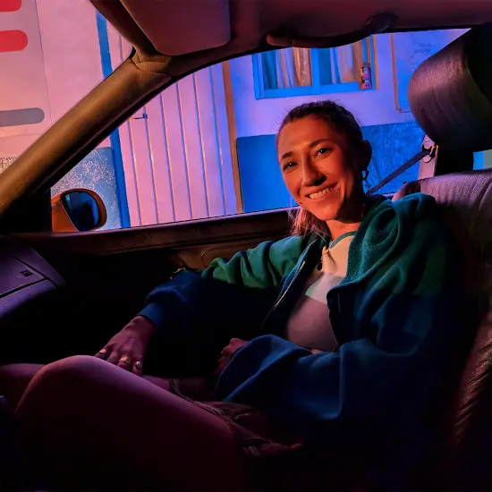 A young woman sits in a car at night