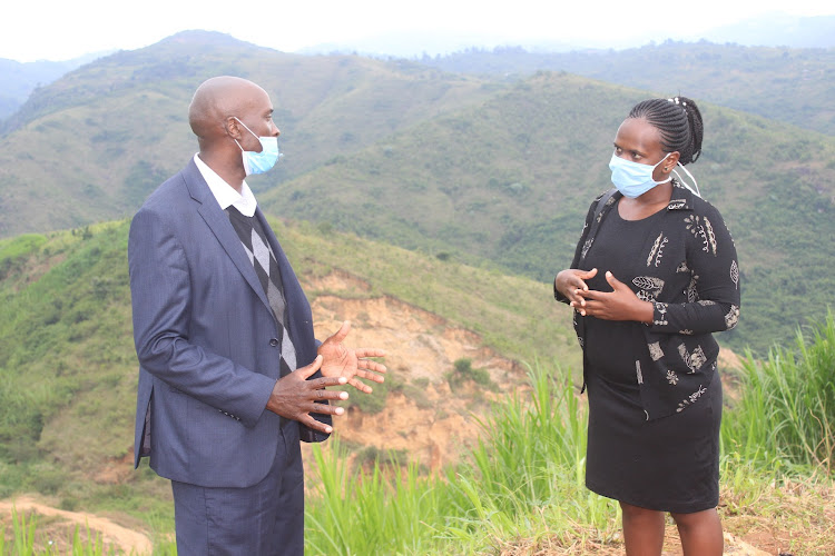 Murang'a county director of meteorology Paul Murage with a farmer in Gaturi area on Tuesday