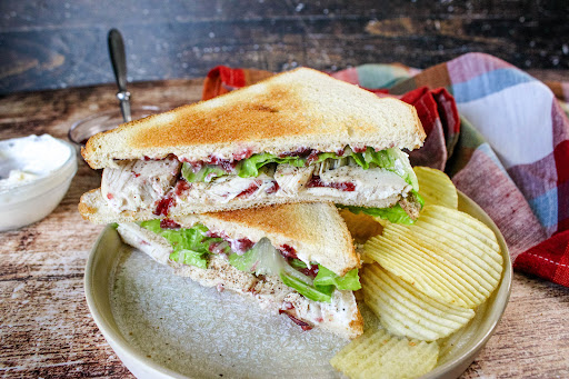 Turkey Cranberry Sandwich on a plate with potato chips.