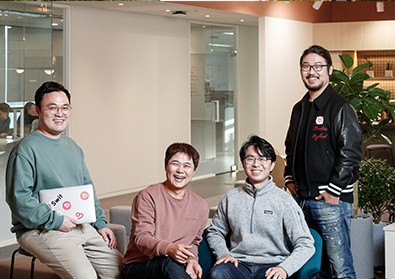 The Swit team are sitting around a couch smiling at the camera.