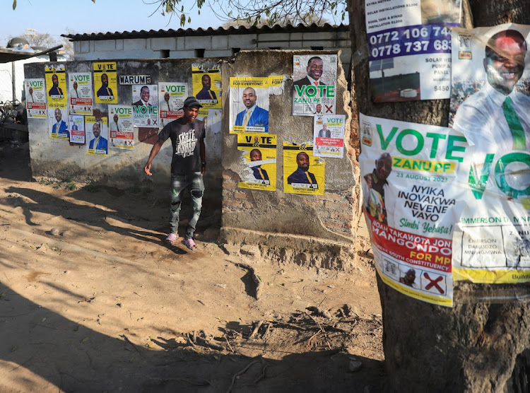 A man walks past election campaign posters in Macheke, Zimbabwe