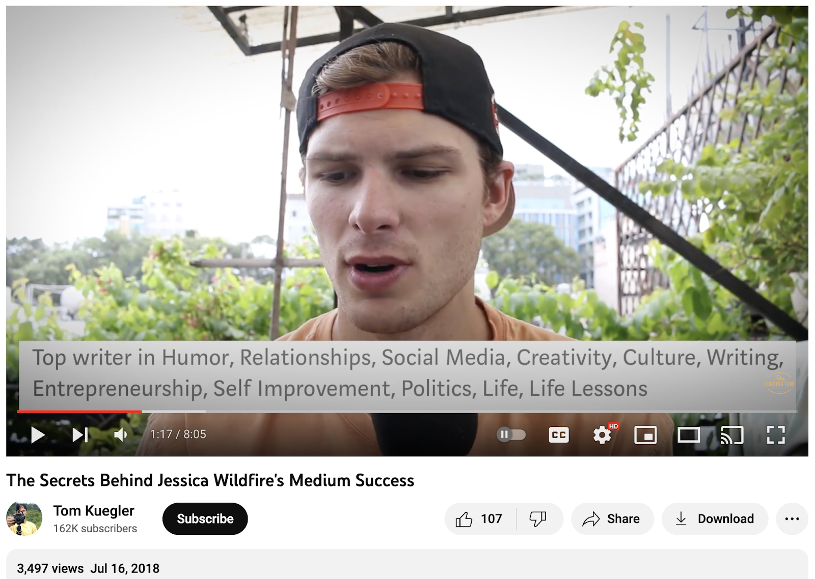 screenshot of a youtube video labeled The Secrets behind Jessica Wildfire’s Medium Success. The youtube channel is called Tom Kuegler and the channel has 162,000 subscribers. 3,497 views and was uploaded on July 16th 2018. The screencap is a video image of a young guy in a cityscape outdoors wearing a cap on his head on backwards and the caption reads Top writer in Humor, relationships, social media, creativity, culture, writing, entrepreneurship, self improvement, politics, life, life lessons