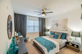 Bedroom with Light Tan Carpet, a Double Window with Blinds, Ceiling Fan, and White Walls