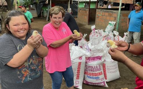 A group of people holding baby chicks 
Description automatically generated