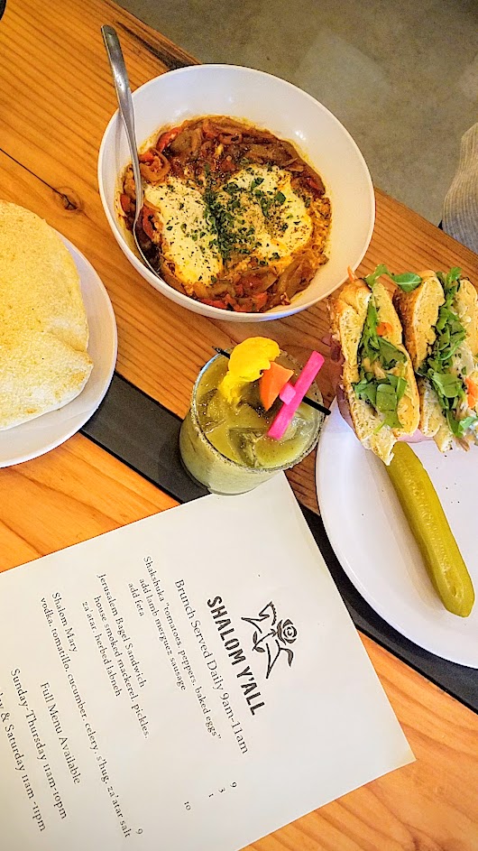 Shalom Y'all options for brunch at Pine Street Market of Shakshuka with tomatoes, peppers, baked eggs; a Jerusalem Bagel Sandwich with house-smoked mackerel, pickles, za’atar, and herbed labneh; and a Shalom Mary with vodka, tomatillo, cucumber, celery, s’hug, and za’atar salt