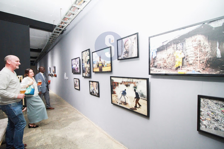 Netherlands Business Hub’s Hello Bartlema and art enthusiasts Annick Deridder and David Ongo’olo examine art on display.