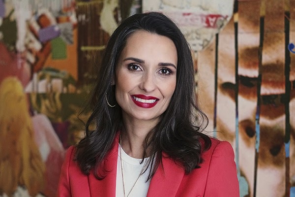 Mujer con cabello castaño lacio y una chaqueta rosa.