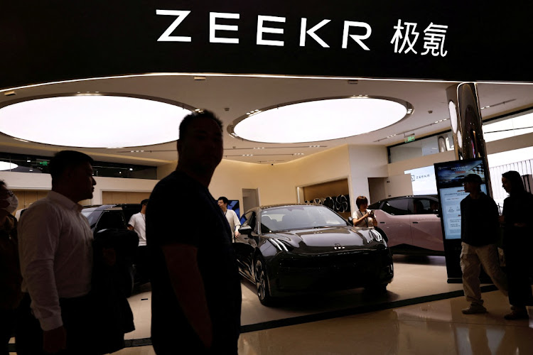 People walk past a booth of Zeekr, Chinese automaker Geely's premium EV brand, at a shopping mall in Beijing on November 3 2023. File Picture: REUTERS/Tingshu Wang