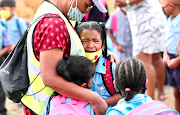 A child holds on to mommy before schooling begins at Blomvlei Primary in Hanover Park.