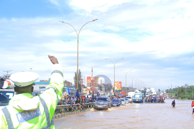 A police officer controls Traffic on the heavily flooded area of Thika Road at the Kenyatta University on May 1, 2024.