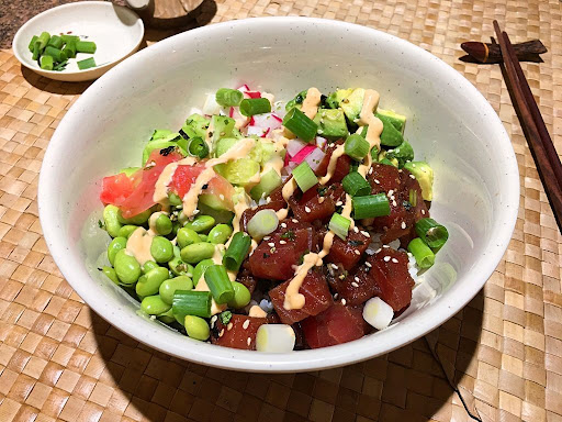 A delicious & healthy poke bowl with sushi rice, tuna, avocado, cucumber, radishes, edamame and pickled ginger.