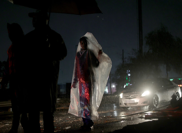 A man covers himself with a plastic sheet during heavy rain in Inanda, north of Durban. Picture: SANDILE NDLOVU