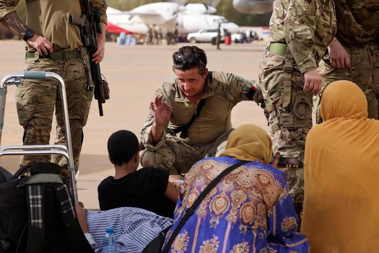 A Royal Marine checks on a child among the evacuees while waiting for an aircraft bound for Cyprus, at Wadi Seidna airport, Sudan, April 27 2023. Picture: UK MOD/REUTERS