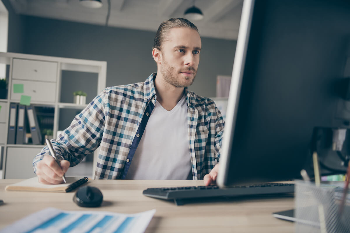 Entrepreneur using a computer and writing on a notebook