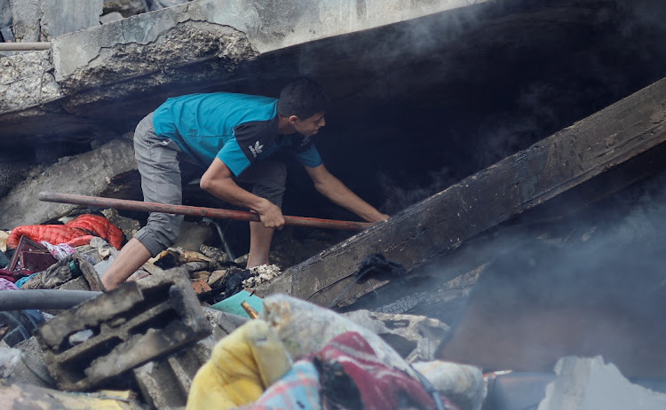 A Palestinian searches under the rubble in the aftermath of Israeli strikes, amid the ongoing conflict between Israel and the Palestinian Islamist group Hamas, in Khan Younis in the southern Gaza Strip, October 14, 2023.