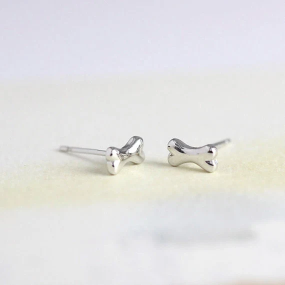 Brincos de Studs Osso da Sorte Little Wish. Pequenos e charmosos, trazem um toque de sorte e estilo ao seu visual diário, perfeitos para qualquer ocasião.