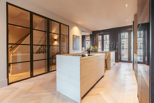 Modern kitchen with island and glass staircase in this luxury apartment / penthouse for sale in Amsterdam ($2,319,325 - 143 m²)