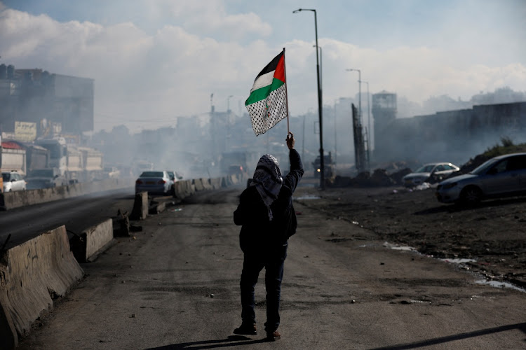 A man walks with a Palestinian flag in the West Bank, December 27 2022. Picture: MOHAMAD TOROKMAN/REUTERS