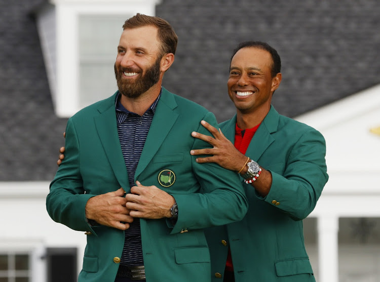 Dustin Johnson is presented with the green jacket by Tiger Woods after winning The Masters at Augusta National Golf Club on November 15, 2020