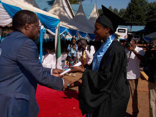 Embu governor Martin Wambora awards a Fidesia School of Nursing graduate with a diploma certificate yesterday /REUBEN GITHINJI