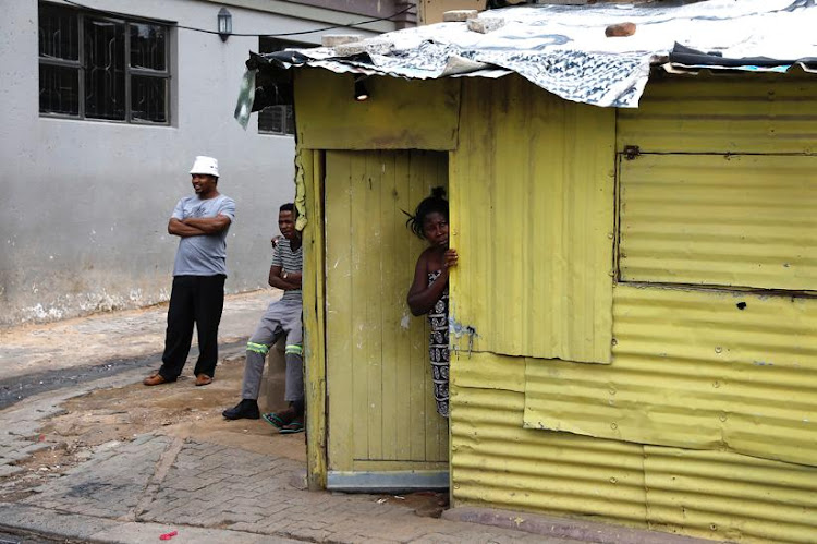 Community members look on as members of the health services disinfect the Madala hostel in Alexandra, Johannesburg, in efforts to control the Covid-19 pandemic.