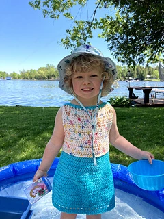 little girl wearing a crocheted dress at the lake