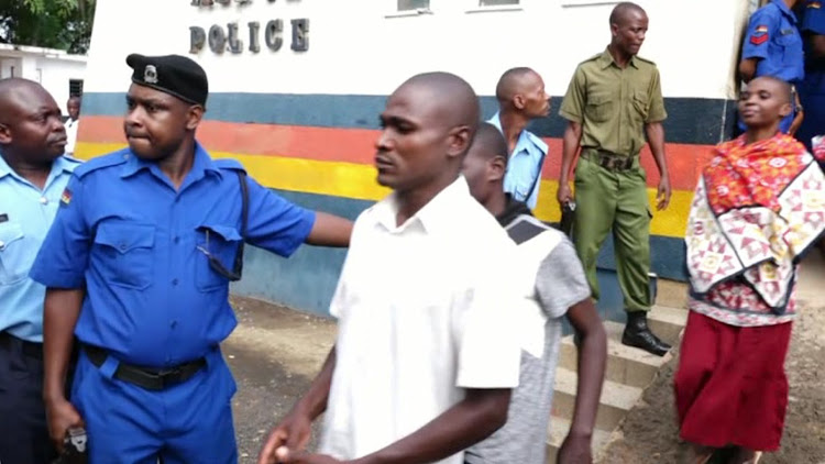 Followers of the controversial preacher Paul Mackenzie being escorted to a police Landcruiser from Malindi Police station to the Malindi law courts .