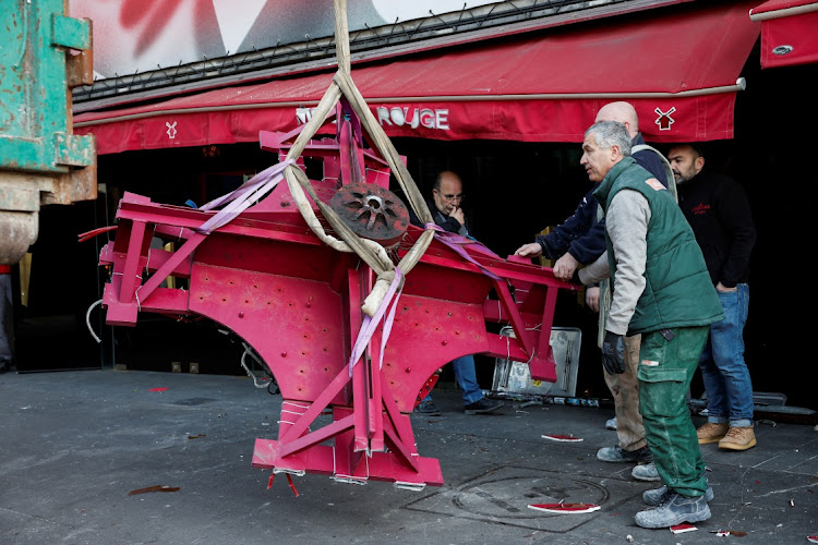 The broken sails of the Moulin Rouge's red windmill are taken away after they fell off during the night in Paris.