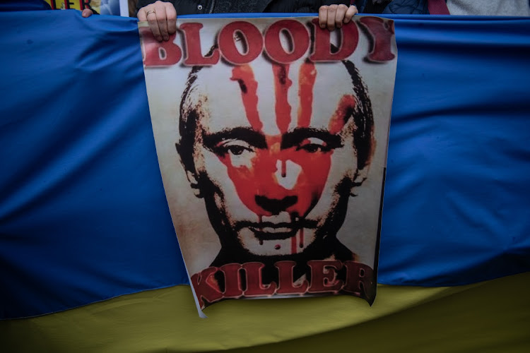 A poster depicting Russian President Vladimir Putin is seen as Ukranians gather in protest outside the Russian Consulate on February 25 2022 in Istanbul, Turkey. Picture: GETTY IMAGES/BURAK KARA