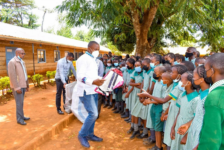 Ndenderu ward MCA Solomon Kinuthia gives pupils of Wangunyu primary school the bags