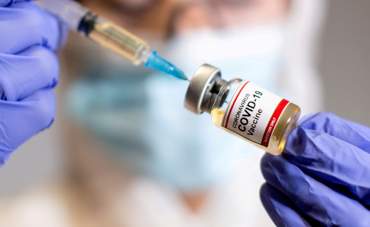 A woman holds a small bottle labeled with a "Coronavirus COVID-19 Vaccine" sticker and a medical syringe in this illustration taken October 30. File Photo